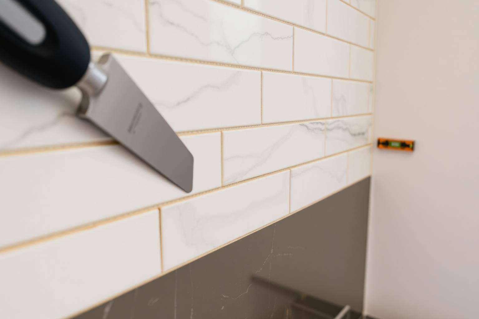 Marble subway tile backsplash being installed with spacers